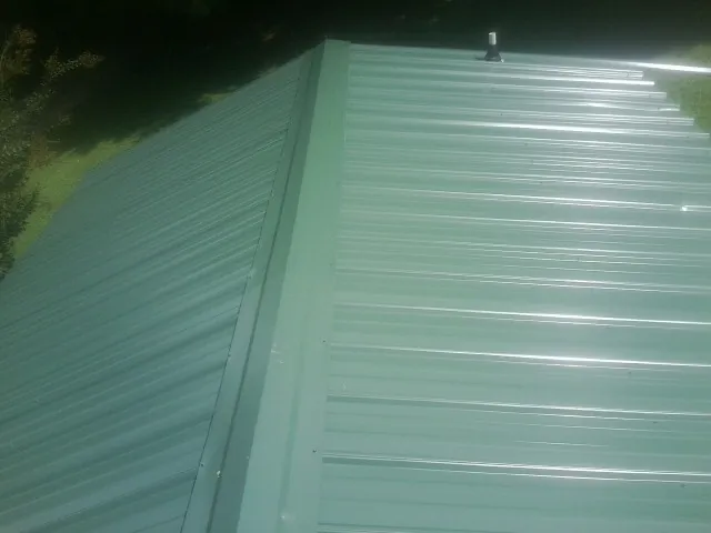 New green metal panels meeting at the ridge of a roof — Flat Roof Repair work by our crew in Washington